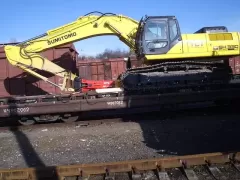 Transshipment of construction equipment onto railway cars in the port of Ilyichevsk, Ukraine. Mounting a Sumitomo excavator on a railway platform. 